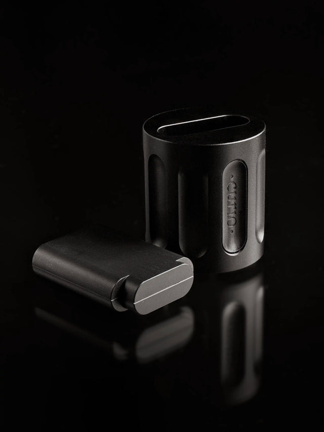 A black Curio Column Puzzle sits disassembled with the shuddle laying flat next to the colmn on a balck background