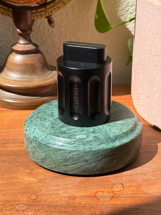 The black Curio Column Puzzle displayed on the Rajasthan Green marble Curio Plinth, lifestyle desk shot with globe