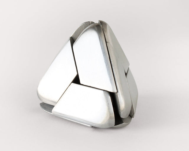 The stainless steel Craighill Tetra Puzzle nearly assembled on a gray background
