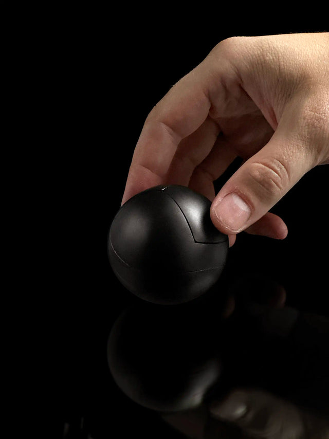 A hand reaches for a black Craighill Venn Puzzle on a black background.