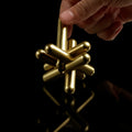 Hand pulling apart the brass Craighill Jack Puzzle on Black background