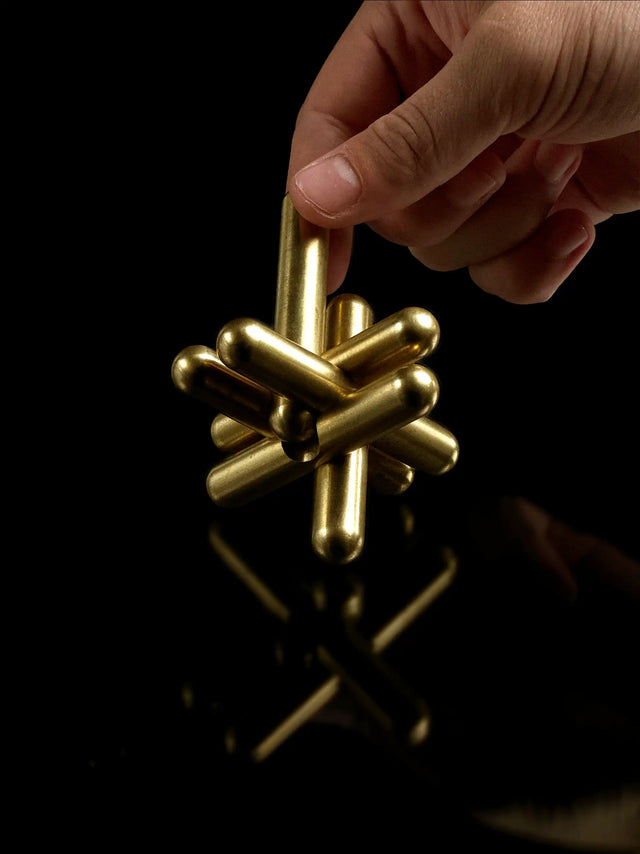 Hand pulling apart the brass Craighill Jack Puzzle on Black background