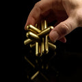 Hand holding the brass Craighill Jack Puzzle on Black background