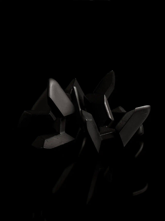 A black Craighill Tetera Puzzle sits disassembled on a black background.