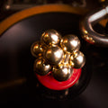 The iridescent Curio Atom Puzzle resting on a vinyl record on a turntable, lifestyle editorial shot