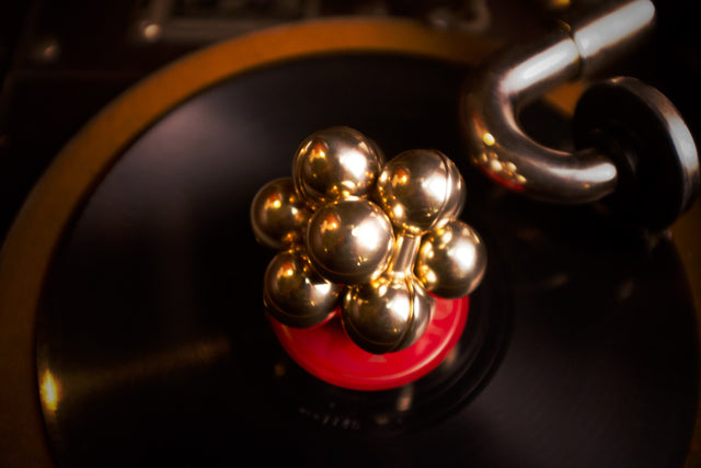 The iridescent Curio Atom Puzzle resting on a vinyl record on a turntable, lifestyle editorial shot
