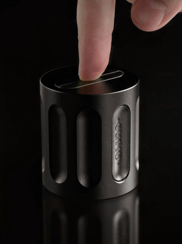 An index finger attempts to assemble a Curio Column Puzzle on a black background