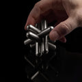 The stainless steel Craighill Jack Puzzle fully disassembled on a black background