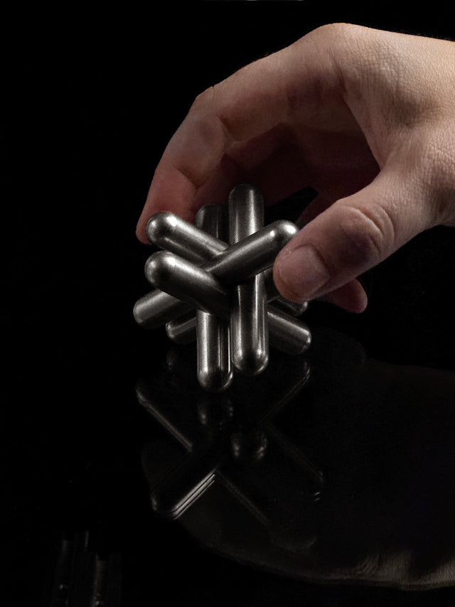 The stainless steel Craighill Jack Puzzle fully disassembled on a black background