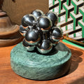 The silver Curio Atom Puzzle assembled on the Rajasthan Green marble Curio Plinth, lifestyle desk shot