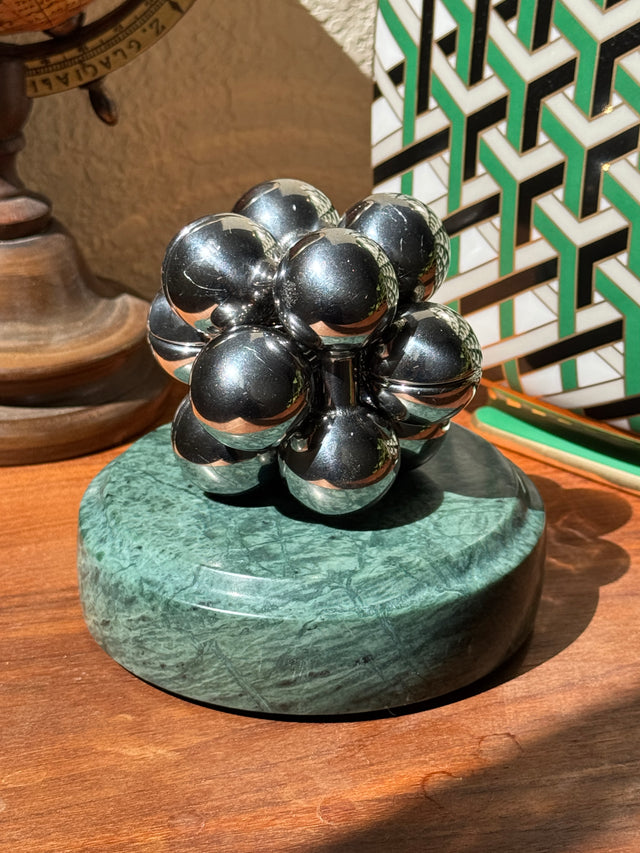 The silver Curio Atom Puzzle assembled on the Rajasthan Green marble Curio Plinth, lifestyle desk shot
