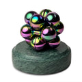 An iridescent Curio Atom Puzzle resting on a Rajasthan Green Curio Plinth on a white background