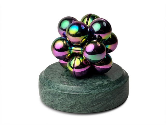 An iridescent Curio Atom Puzzle resting on a Rajasthan Green Curio Plinth on a white background