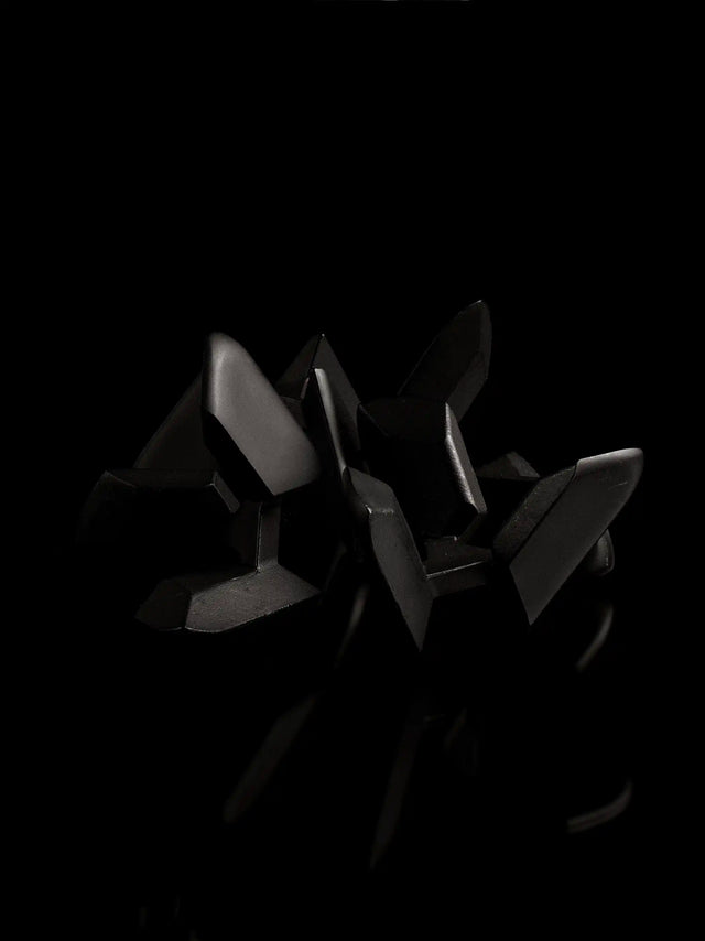 The black Curio Tetra Puzzle disassembled on a black background, angled view