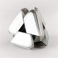 The stainless steel Craighill Tetra Puzzle halfway assembled on a gray background