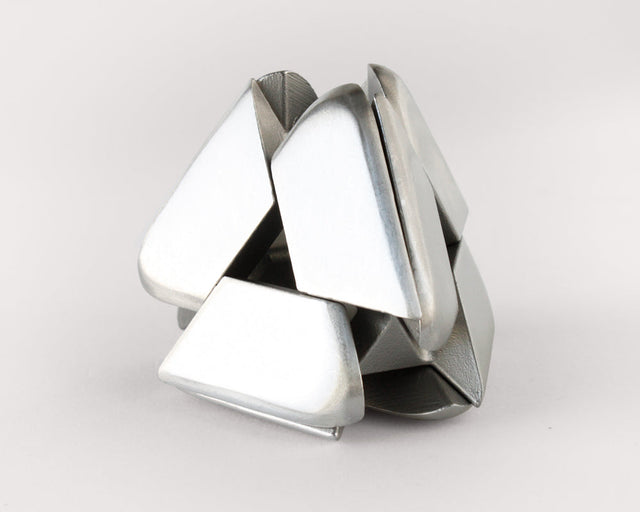 The stainless steel Craighill Tetra Puzzle halfway assembled on a gray background