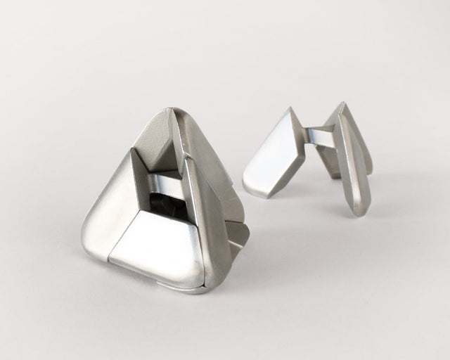 Two stainless steel Craighill Tetra Puzzles displayed together on a gray background