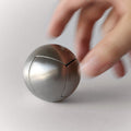 A hand holding the stainless steel Craighill Venn Puzzle on a gray background
